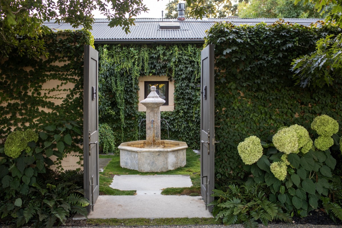 6_Water & Light Stone fountain and lush greenery framed by open doorway, Penning Landscapes water feature design.