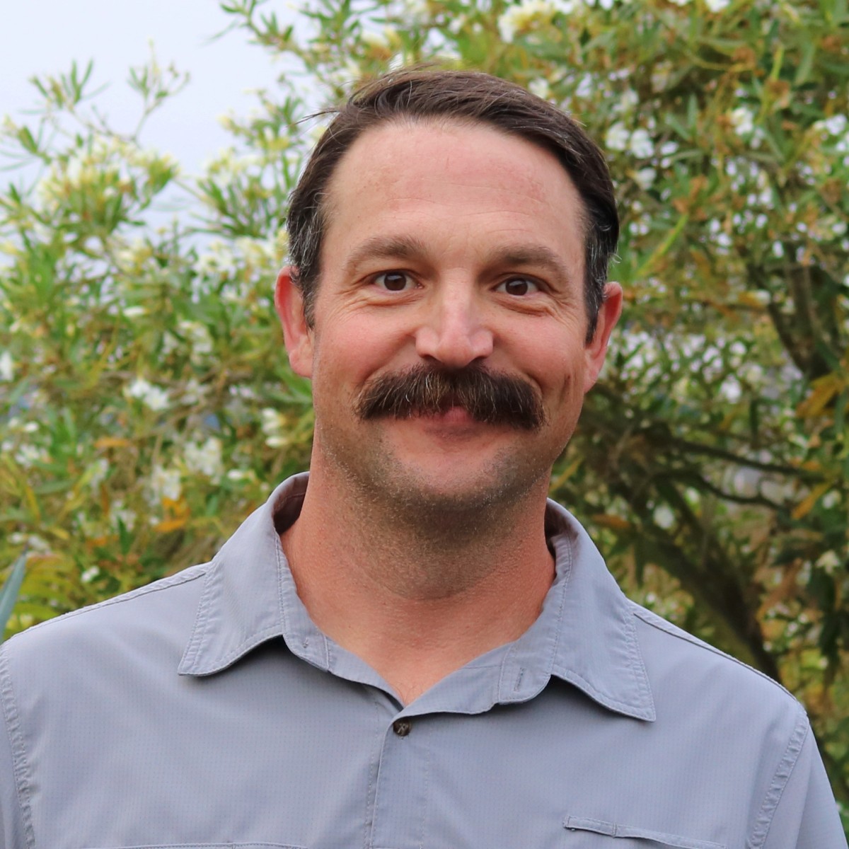 Cody Thomas, Penning Landscapes Irrigation & Water Resource Manager, smiling among foliage.