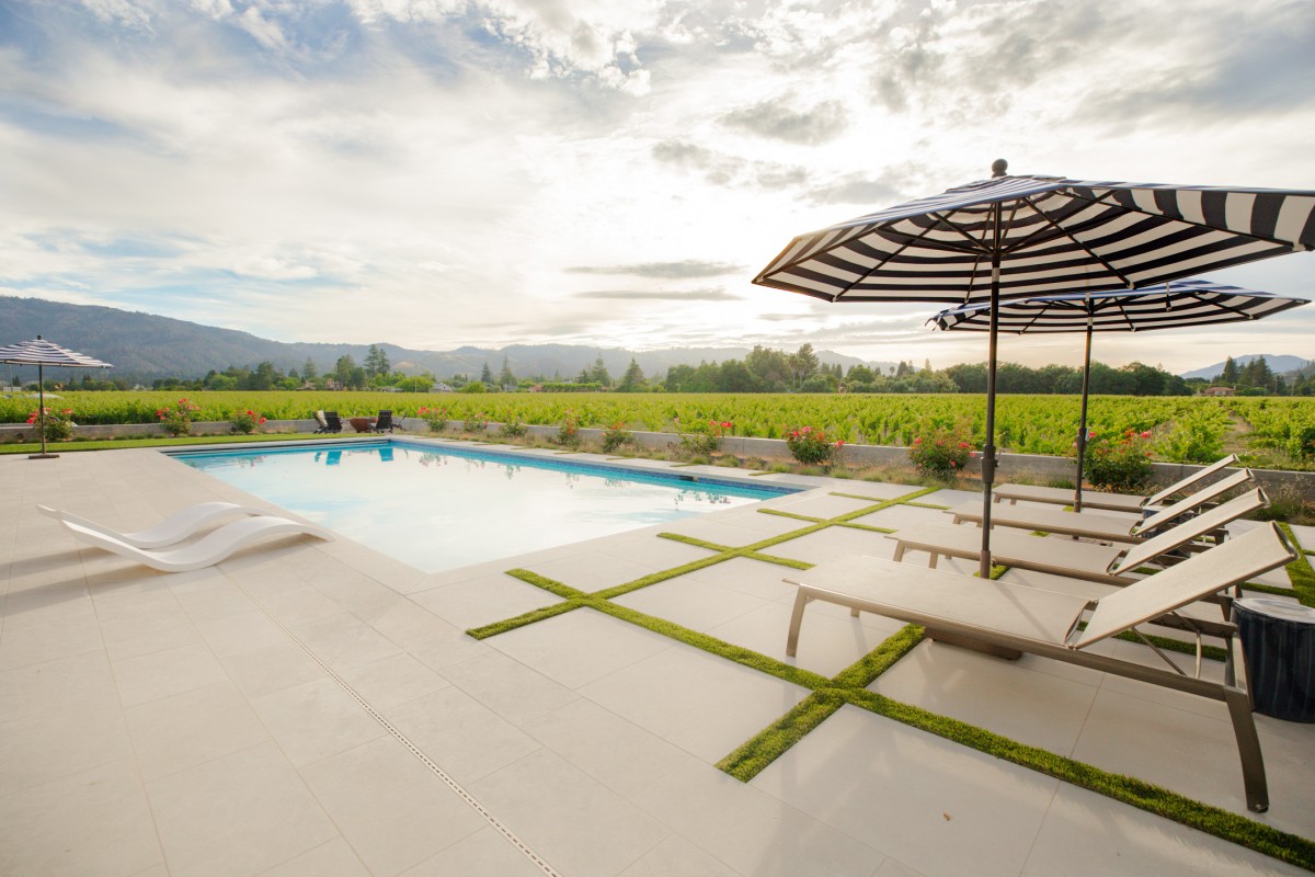 Luxury pool and patio design with lounge chairs and vineyard views in Napa Valley.