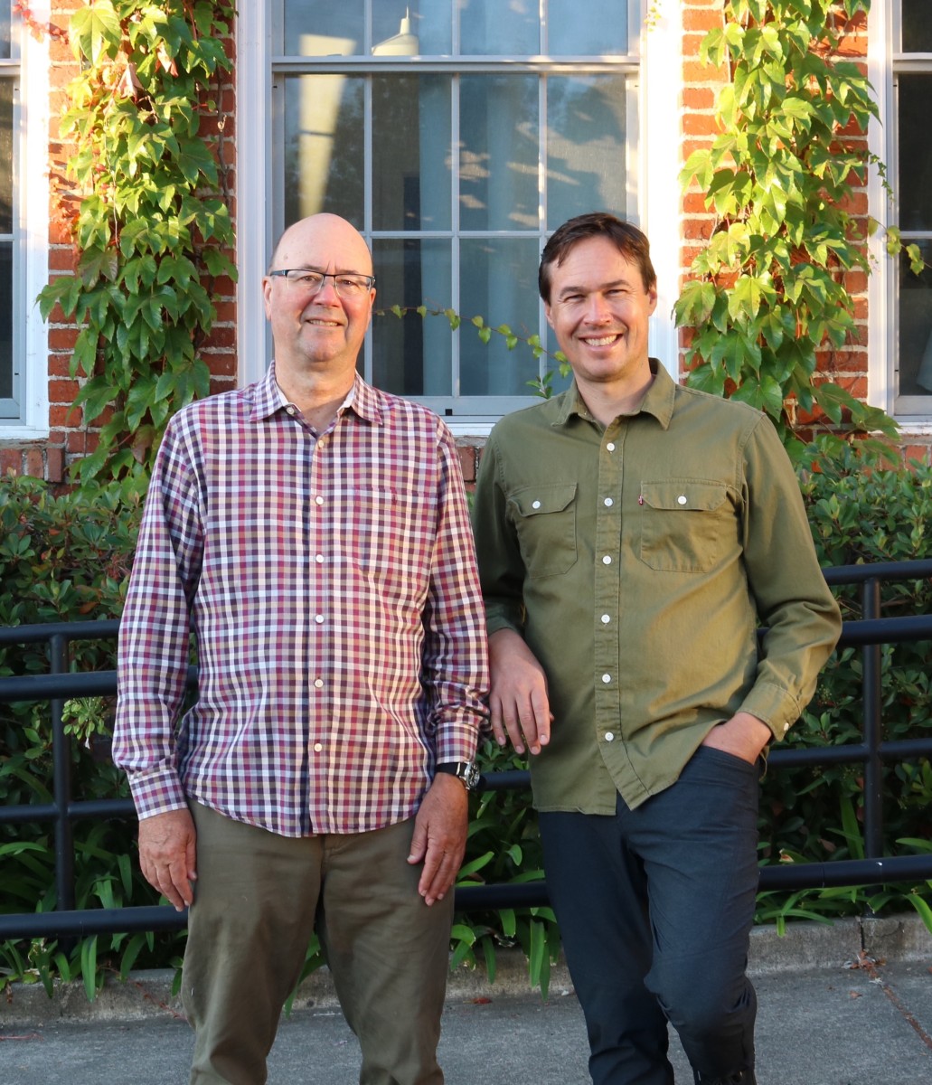 Ben + Lou Horizontal Lou Penning and son, Penning Landscapes team members, standing in front of a brick building with climbing vines.