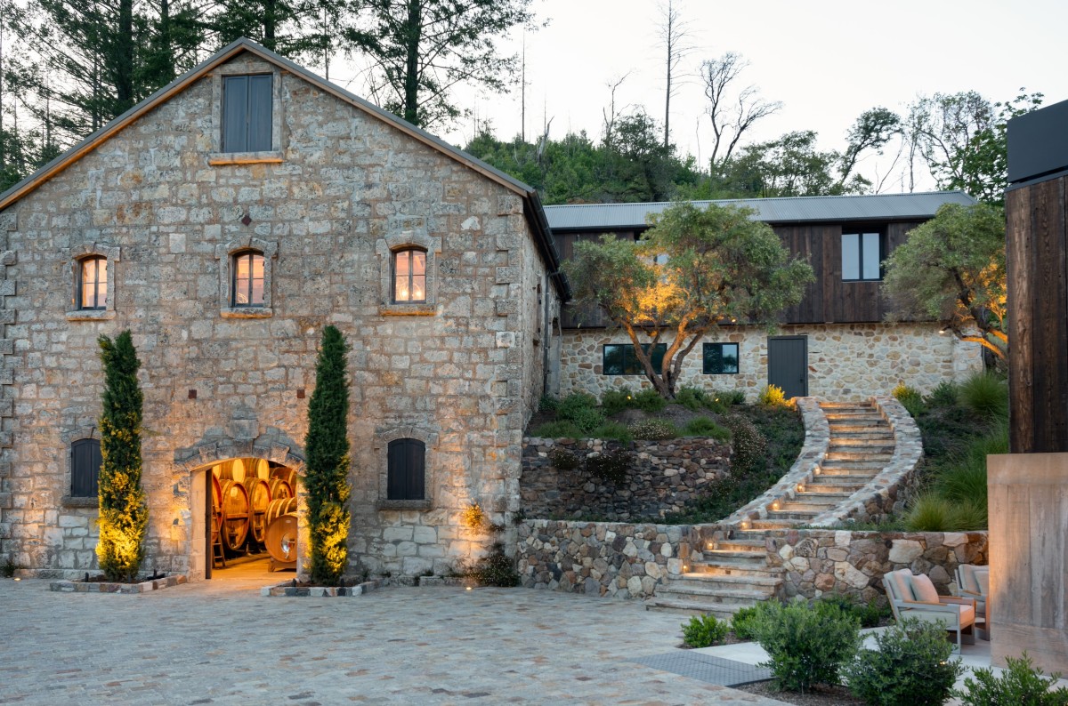 Stone winery building and landscaping with pathway lighting and manicured grounds.